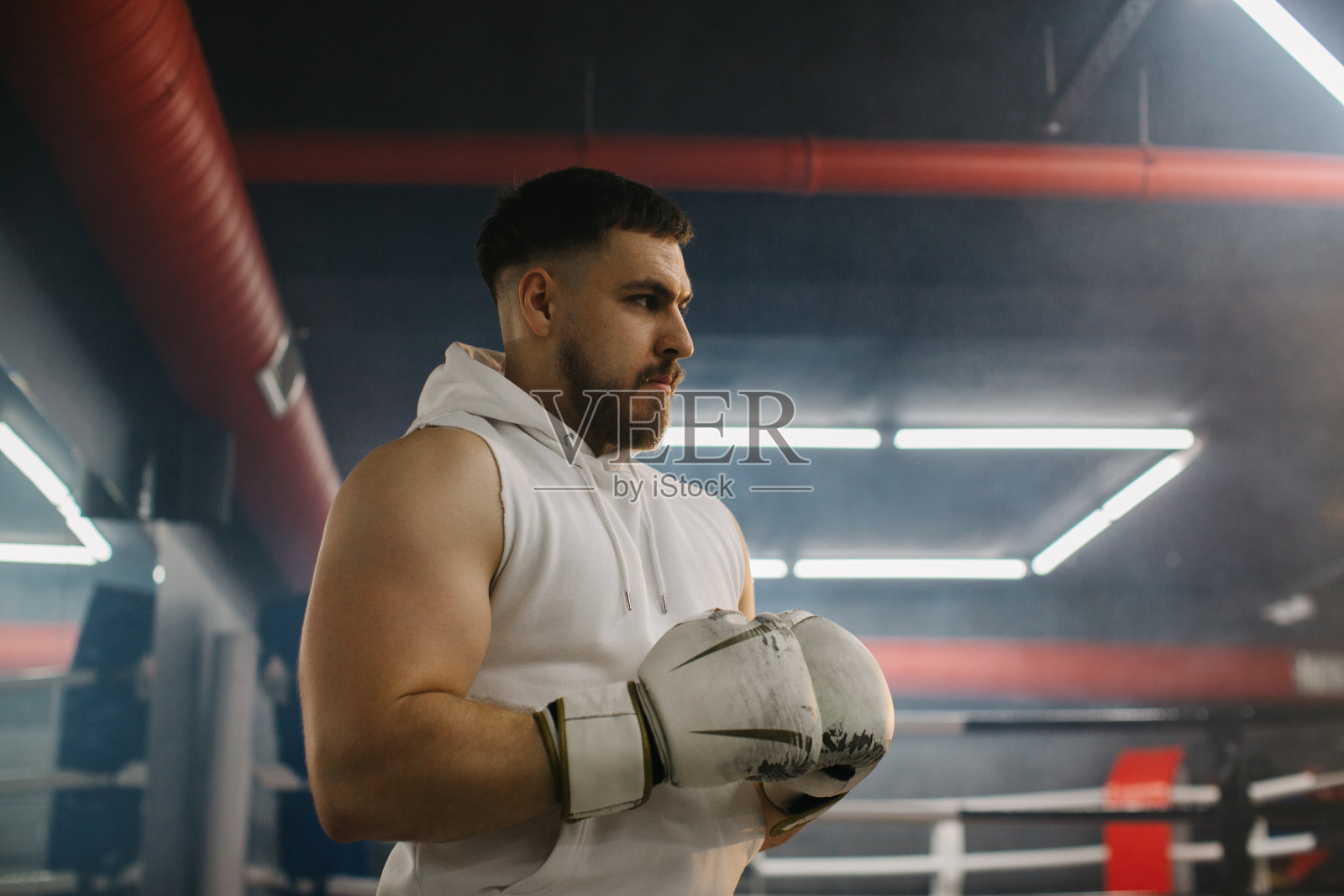 拳击俱乐部拳台背景上戴着手套的男拳击手。照片摄影图片