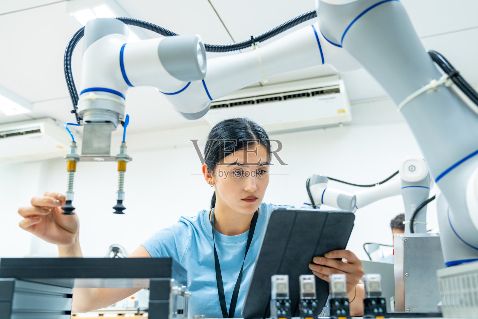 在工厂里操作机器人的女工程师。照片摄影图片