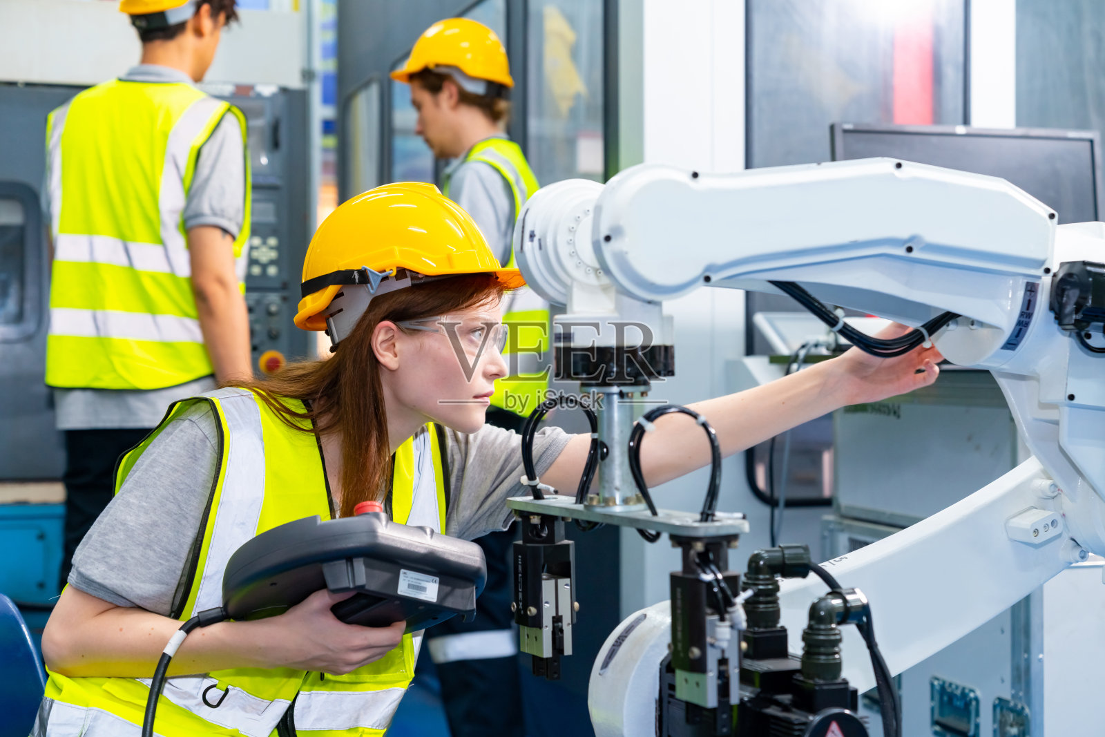 在工厂里操作机器人的女工程师。照片摄影图片