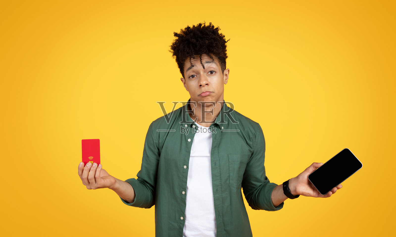 闷闷不乐的黑人年轻人手里拿着手机和信用卡照片摄影图片