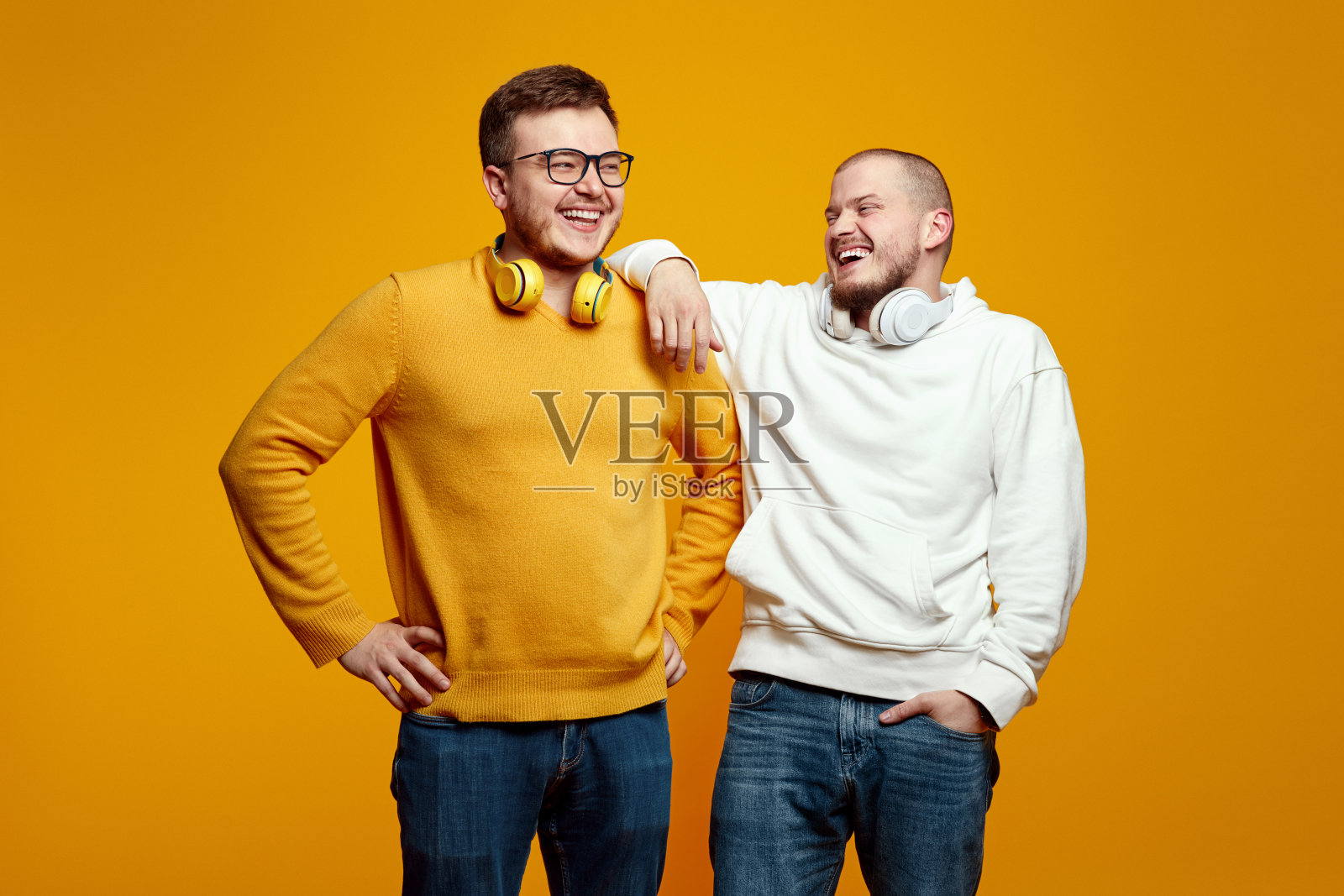 两个英俊的年轻人和朋友戴着耳机在工作室里笑着玩得很开心照片摄影图片