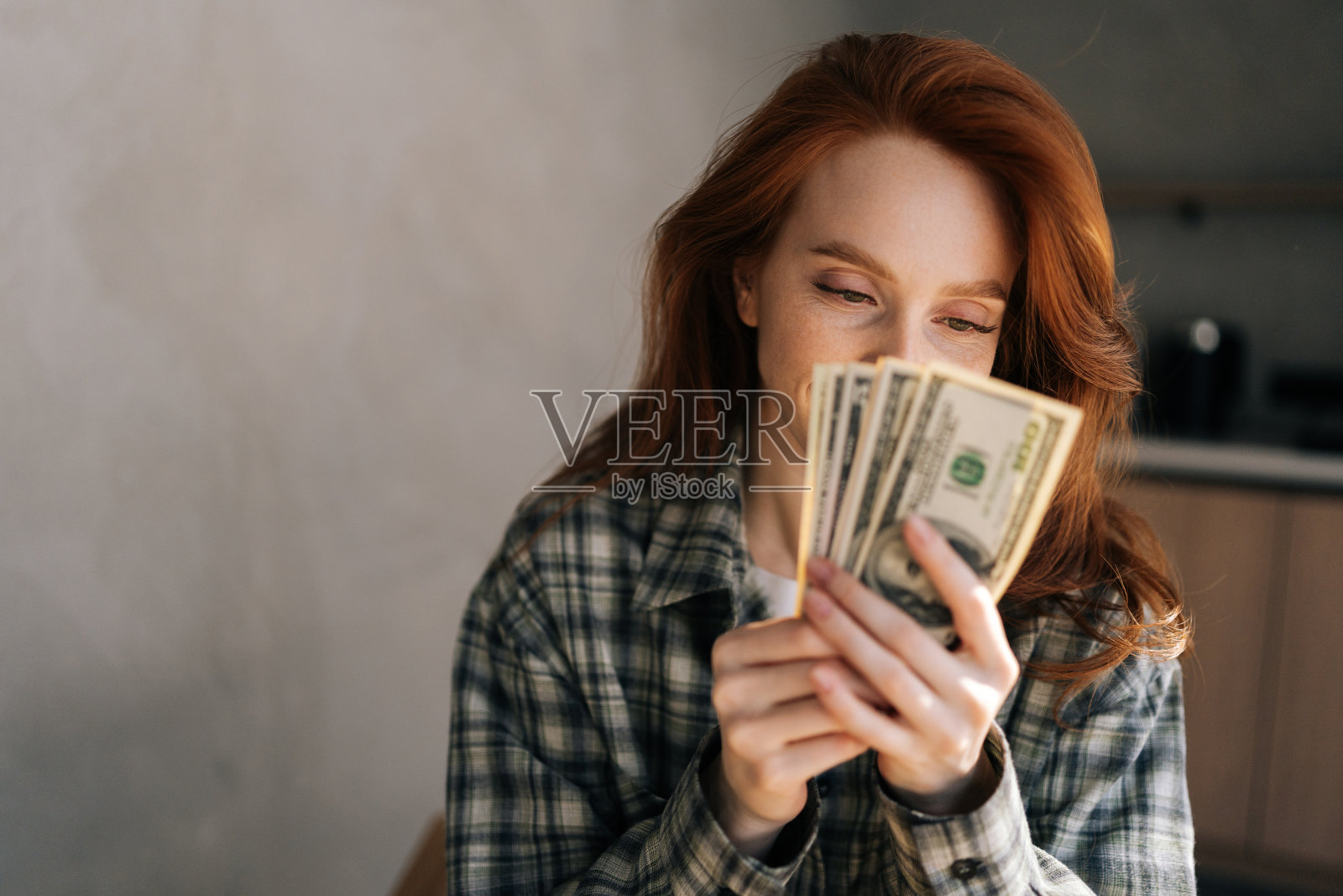 可爱的年轻女子的特写满足于储蓄，快乐地数钱，安全和幸福的财务稳定。快乐的女性对收入感到满意，并节省了钱照片摄影图片