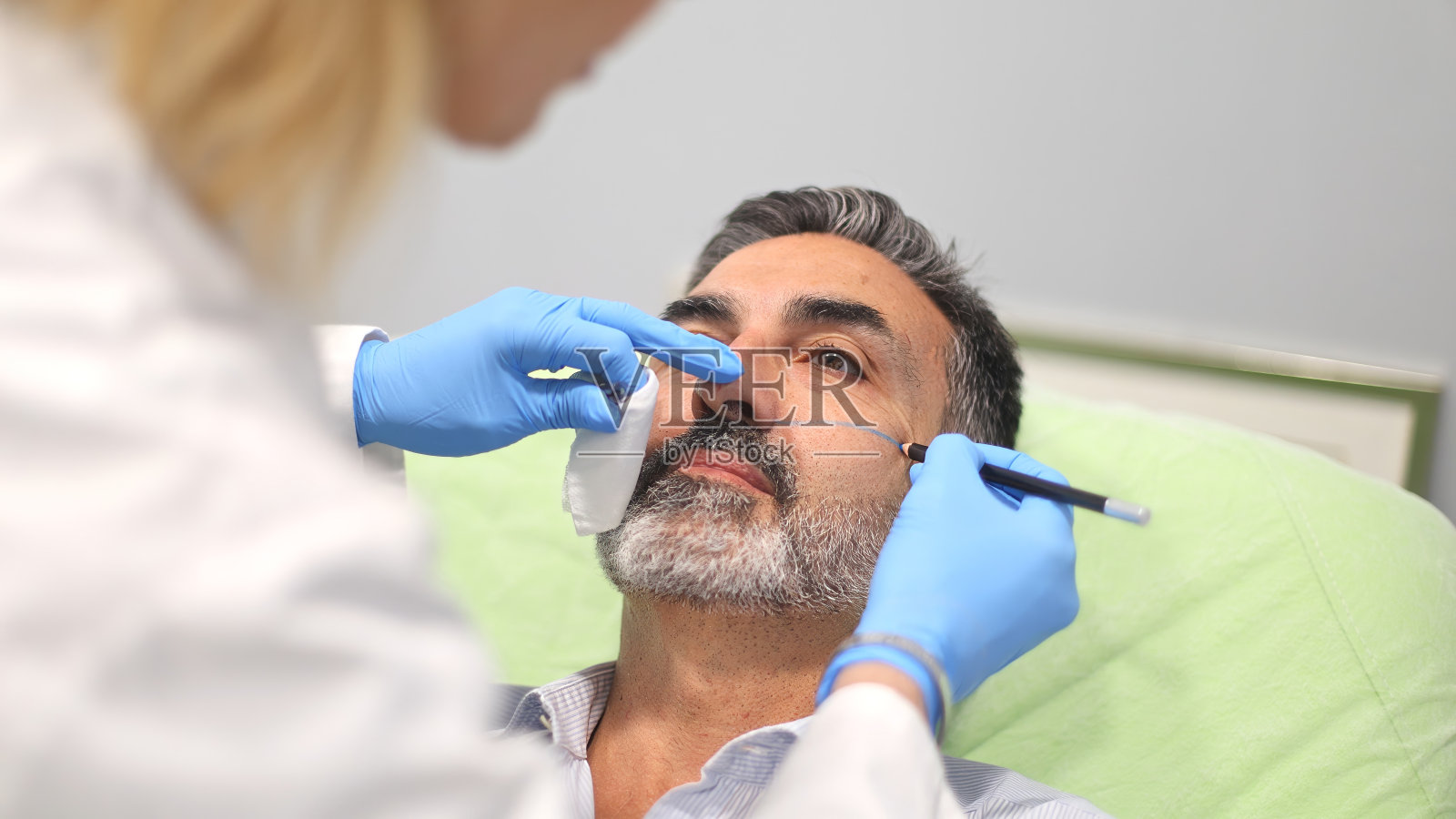 医生在美容诊所给病人做面部标记。照片摄影图片