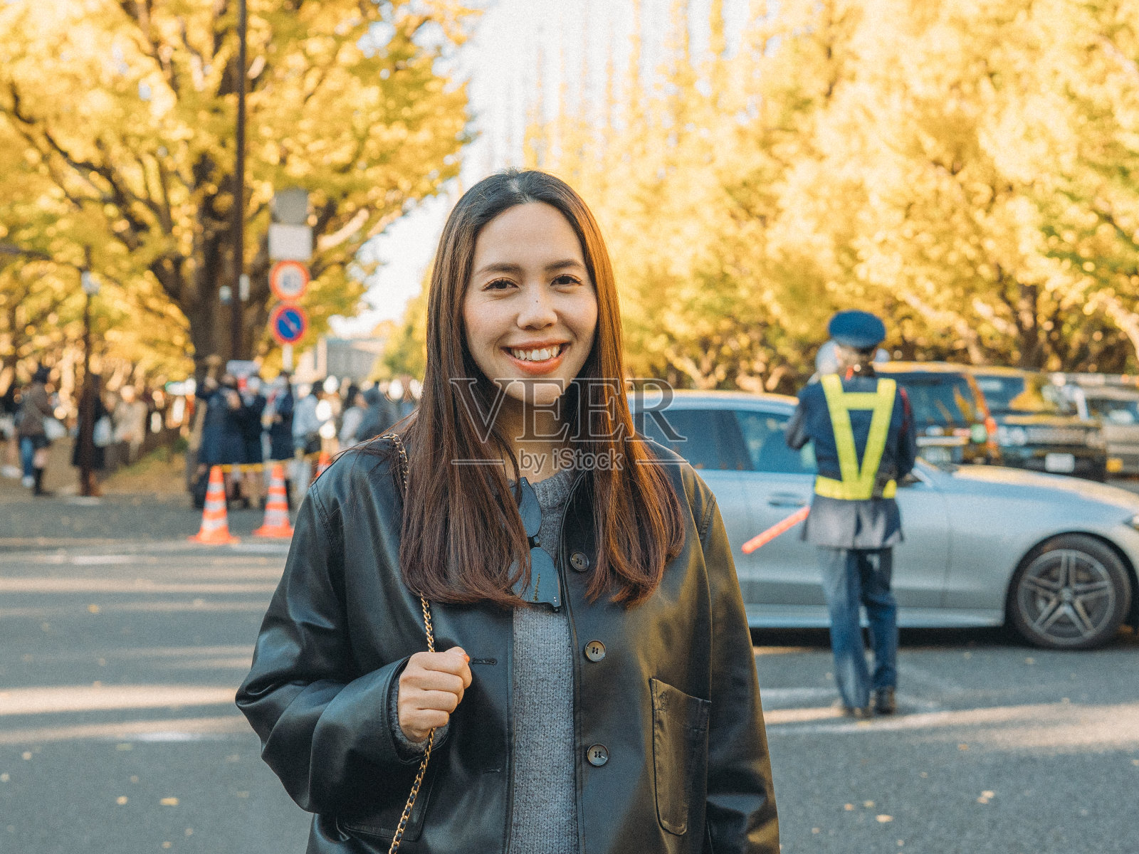 一个温暖的微笑优雅的亚洲妇女的脸，她凝视着下面，笼罩在宁静的秋景。在熙熙攘攘的都市生活中，她在大自然的美丽中找到安慰，反思生活的宁静时刻。照片摄影图片