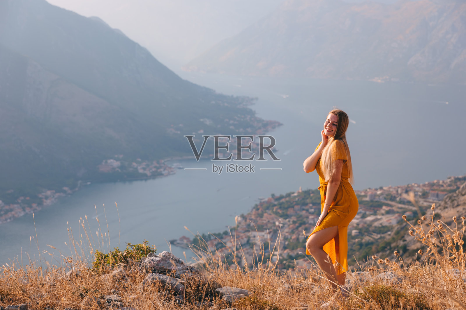 女游客欣赏科托尔的景色。黑山。科托尔湾，科托尔湾，博卡科托尔斯卡和有城墙的古城。照片摄影图片