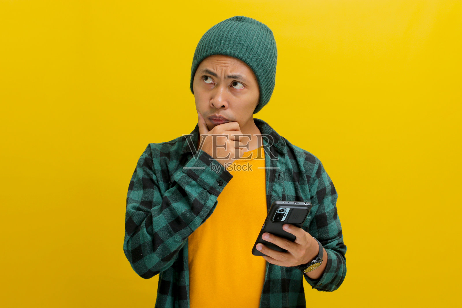 困惑的亚洲男子边看新闻边玩手机照片摄影图片