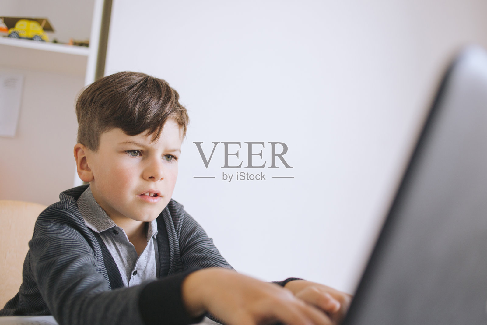 在线远程学习。男学生在家学习。小男孩在家里用笔记本电脑上网交流。在家上学，远程学习，在线学习。在线远程学习。一个学院照片摄影图片