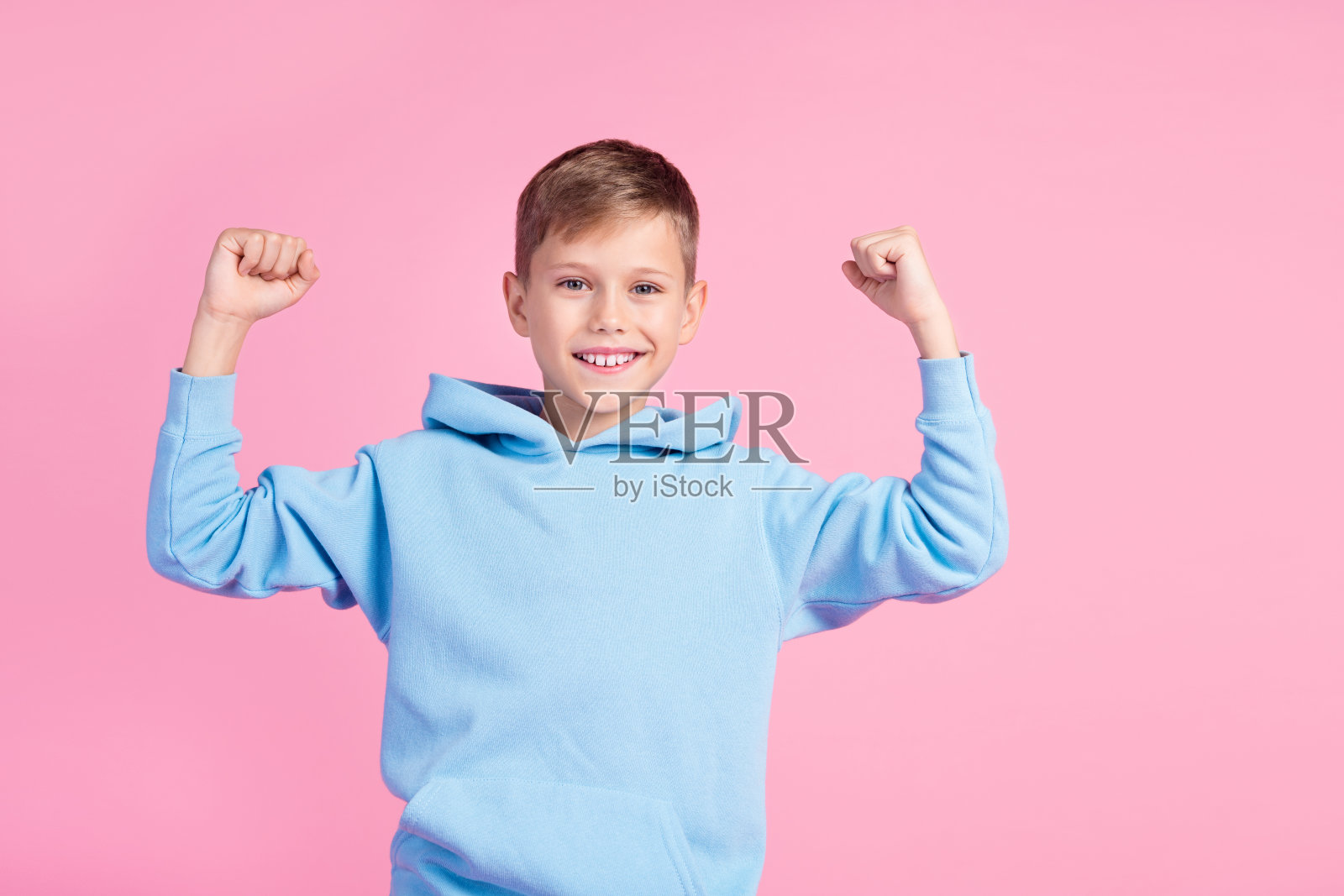 积极的小男孩的肖像笑容灿烂举起拳头胜利空空间孤立在粉红色的背景照片摄影图片