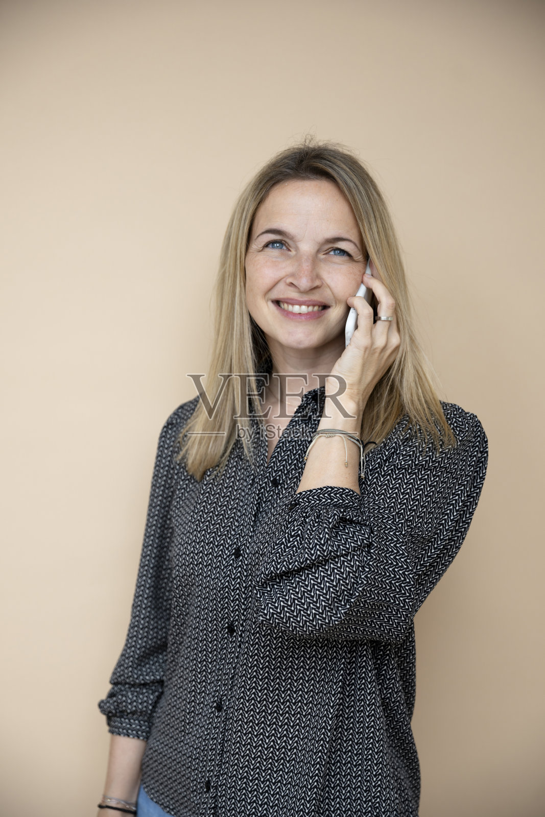 漂亮的40多岁的金发女商人棕色背景前放着智能手机照片摄影图片