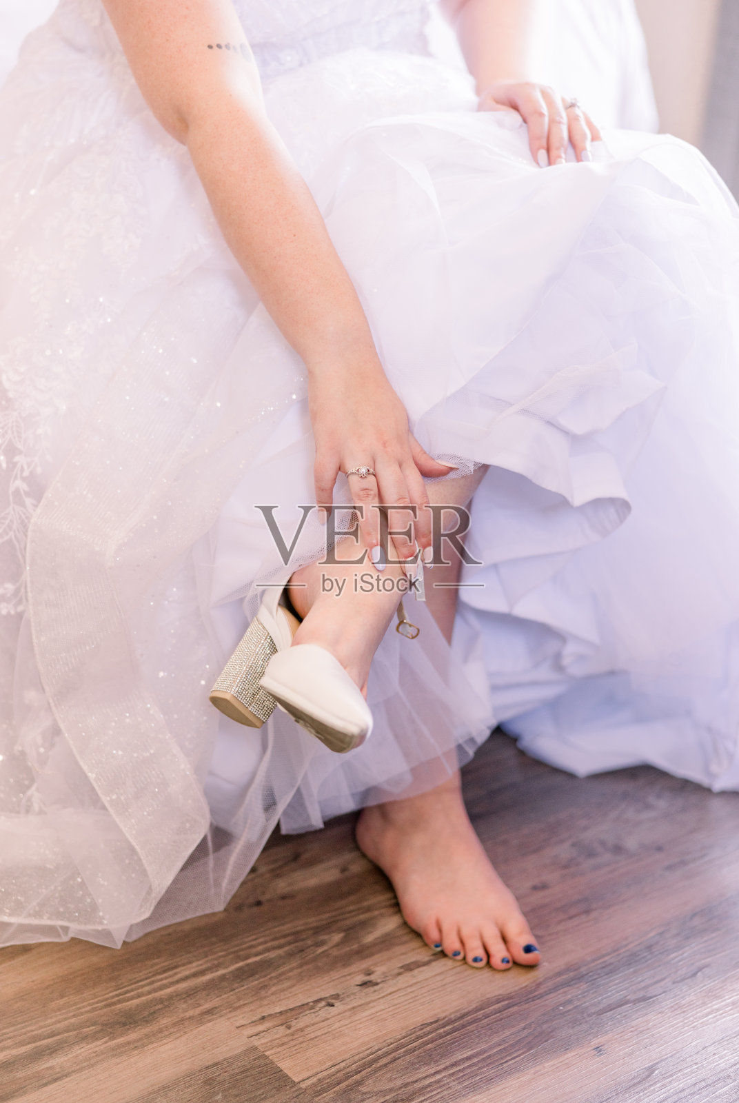婚礼当天，新娘正在穿鞋。她穿着一件宽大的经典婚纱。照片摄影图片