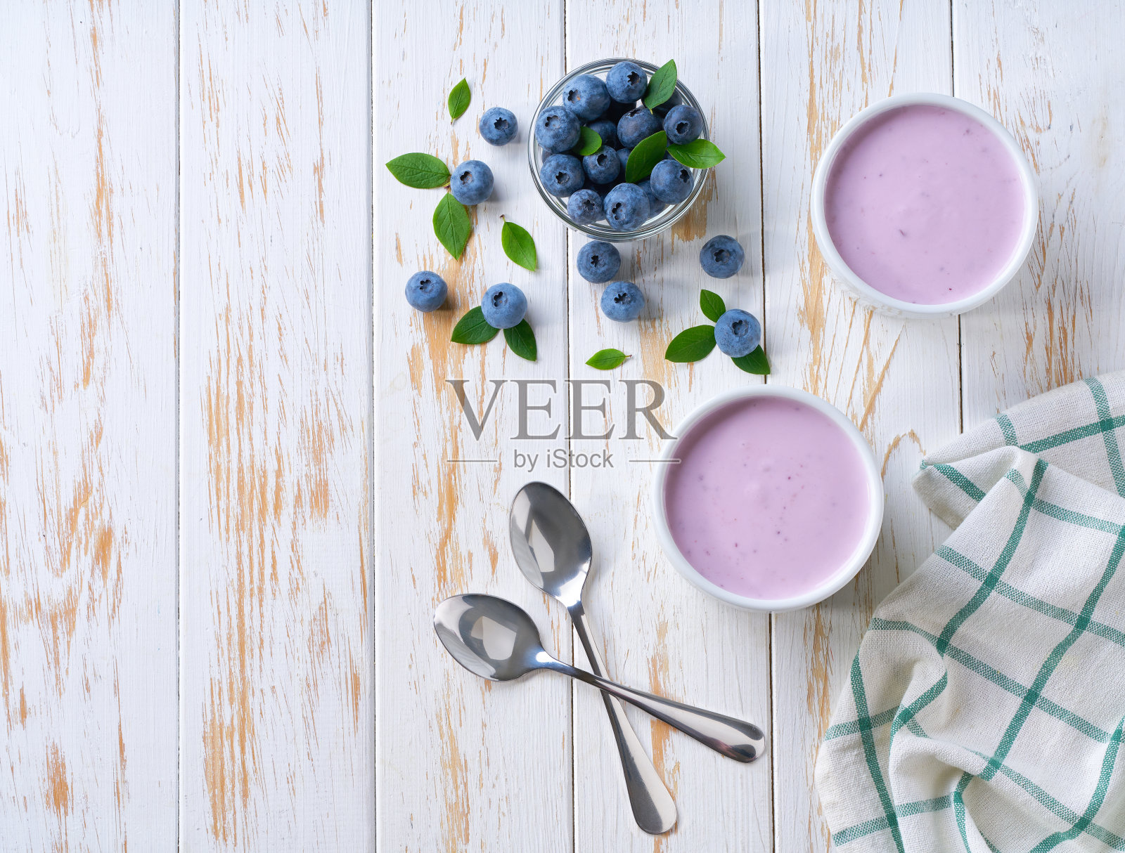 自制水果酸奶与新鲜蓝莓在一个陶瓷碗在浅色背景，俯视图。照片摄影图片