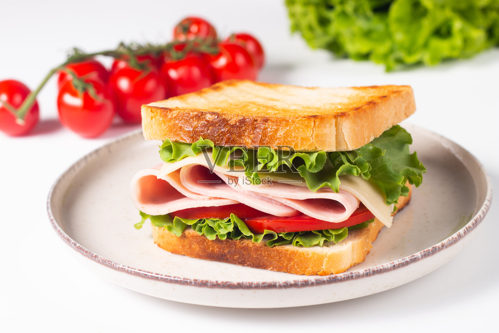 两个三明治的特写，有培根、意大利腊肠、意大利熏火腿和新鲜蔬菜，放在质朴的木制砧板上。俱乐部三明治概念照片摄影图片