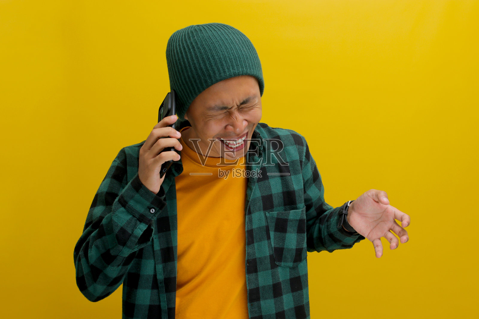 快乐的年轻亚洲男子讲着他的手机，笑着享受愉快的谈话照片摄影图片