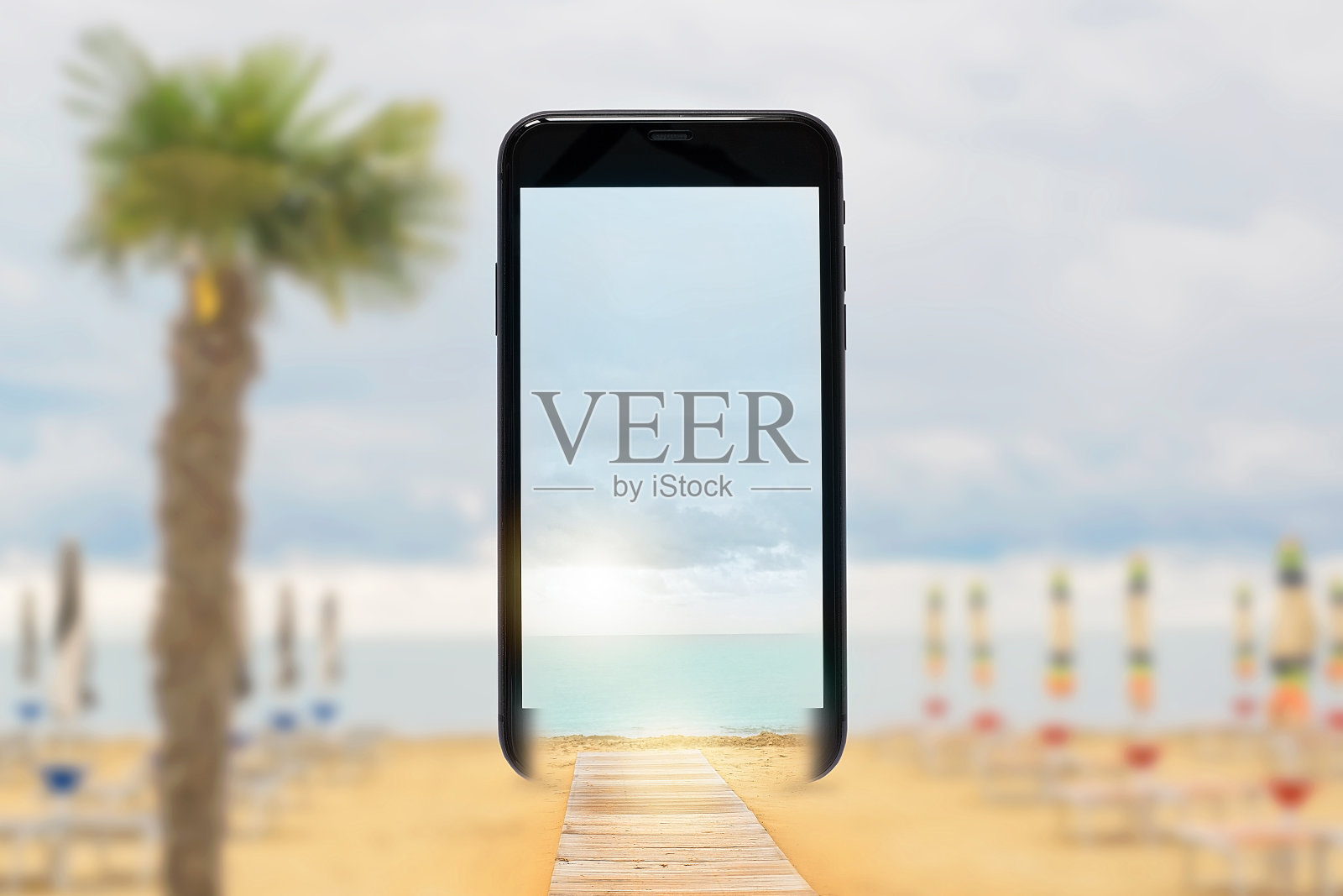 手机屏幕上带着沙滩伞的沙滩照片摄影图片