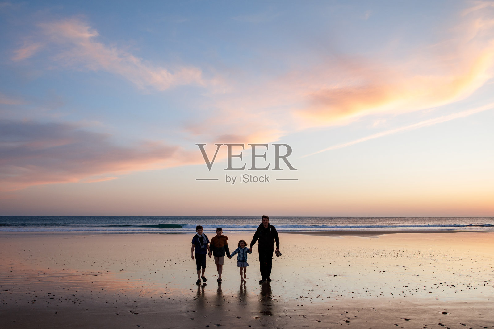 三个孩子和爸爸的肖像剪影，孩子们和爸爸在日落的海滩上快乐地玩耍。幸福的家庭，男人，两个上学的男孩和一个学龄前的小女孩。兄弟姐妹在一起玩耍。成键照片摄影图片