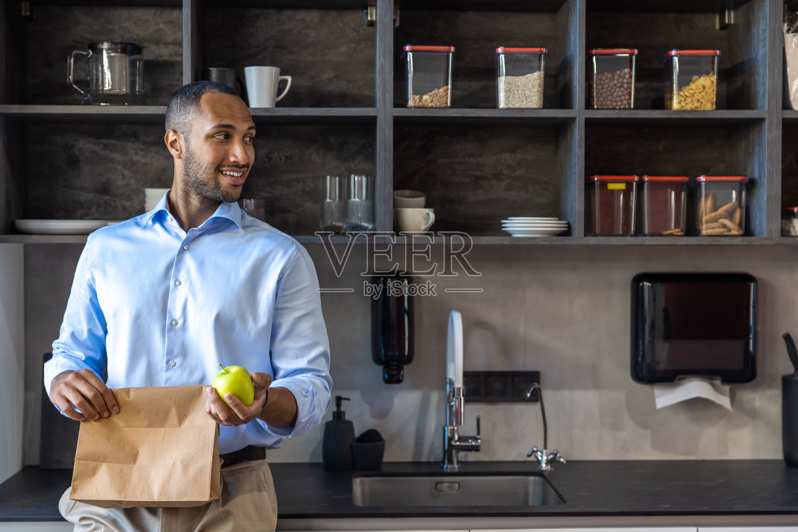 非裔美国商人拿着苹果和纸包照片摄影图片