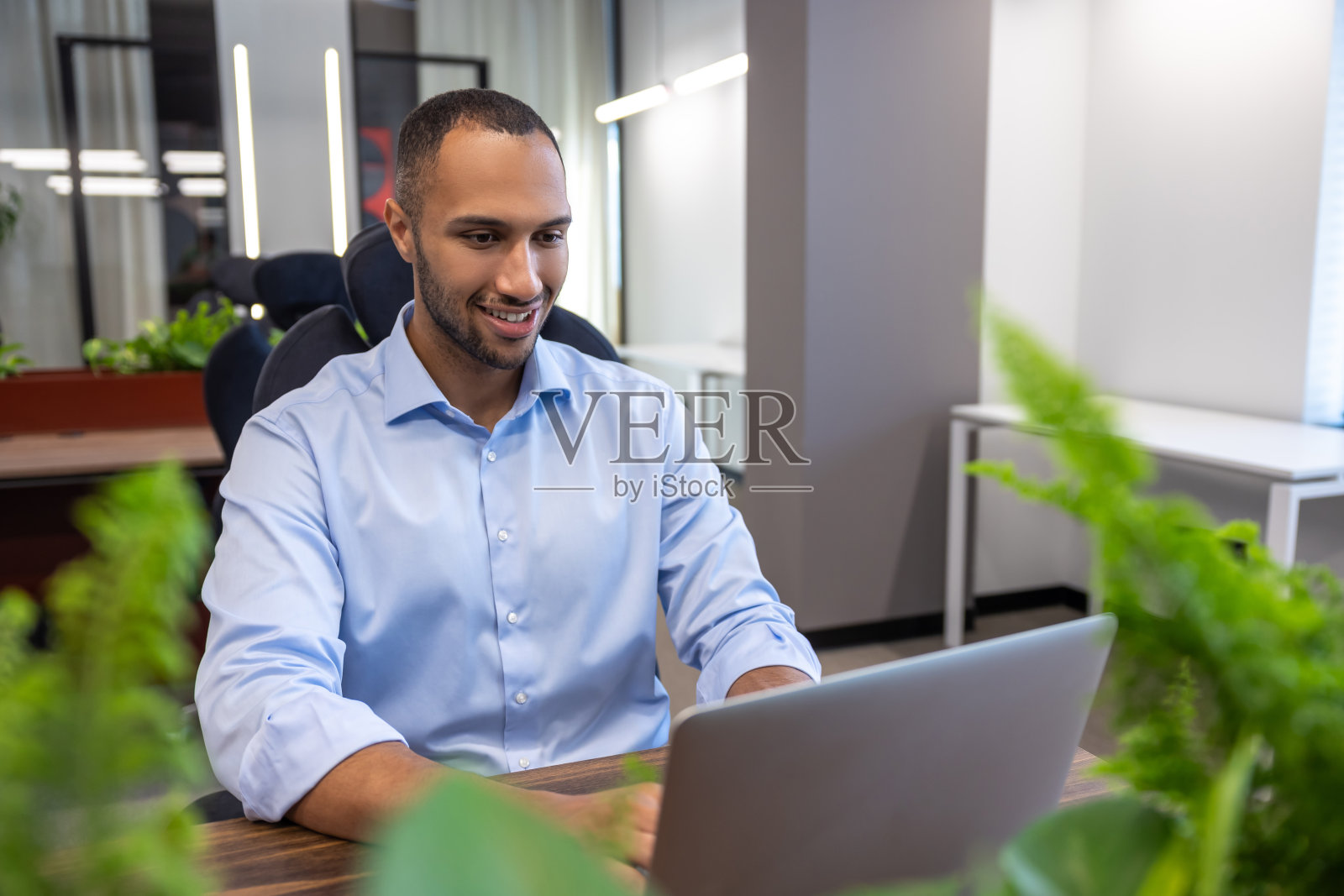 穿着衬衫的比尔登男子在办公室用笔记本电脑工作照片摄影图片