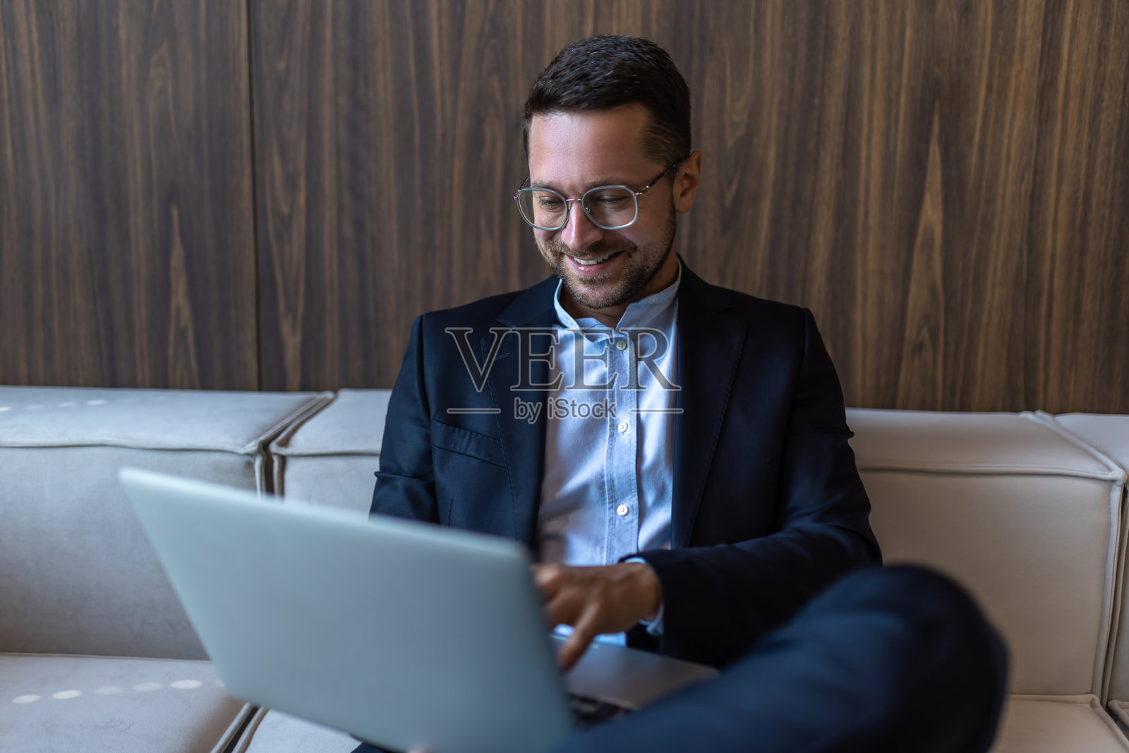 自信的商人戴着眼镜在办公室里用笔记本电脑工作照片摄影图片