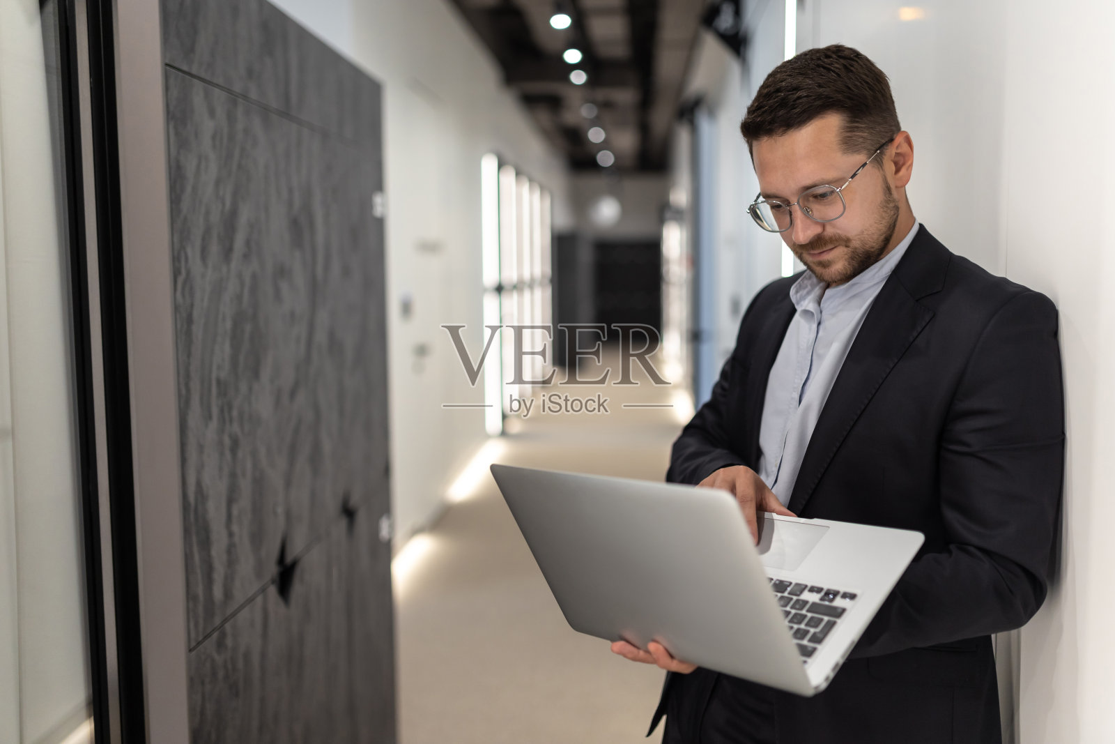 西装革履的成功商人在办公大厅用笔记本电脑工作照片摄影图片