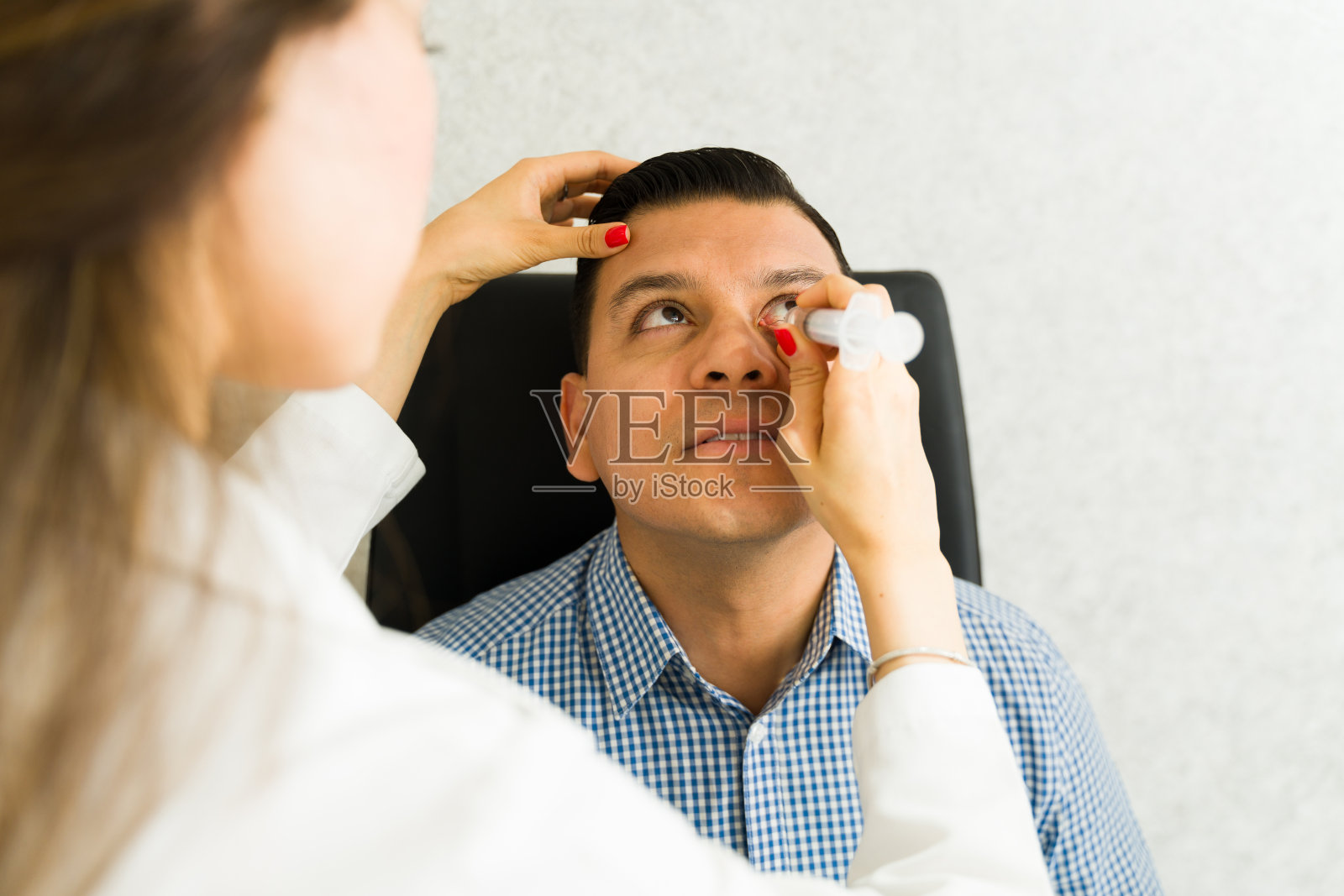 近景:眼科医生在现代诊所用注射器从病人身上取出泪管阻塞照片摄影图片