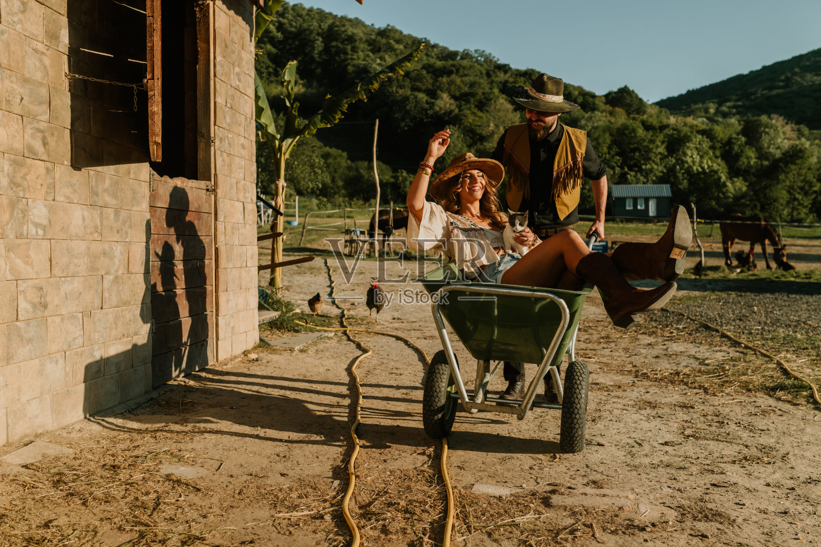 农场主夫妇在马场玩独轮车的正面视图。照片摄影图片