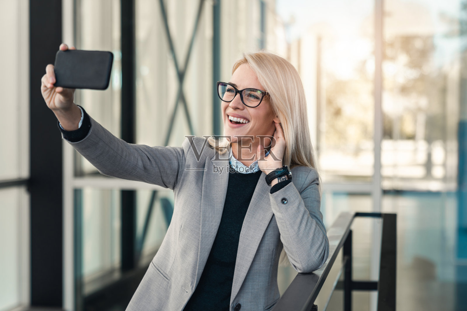 欢快的女员工站在大厅里用智能手机打视频电话照片摄影图片