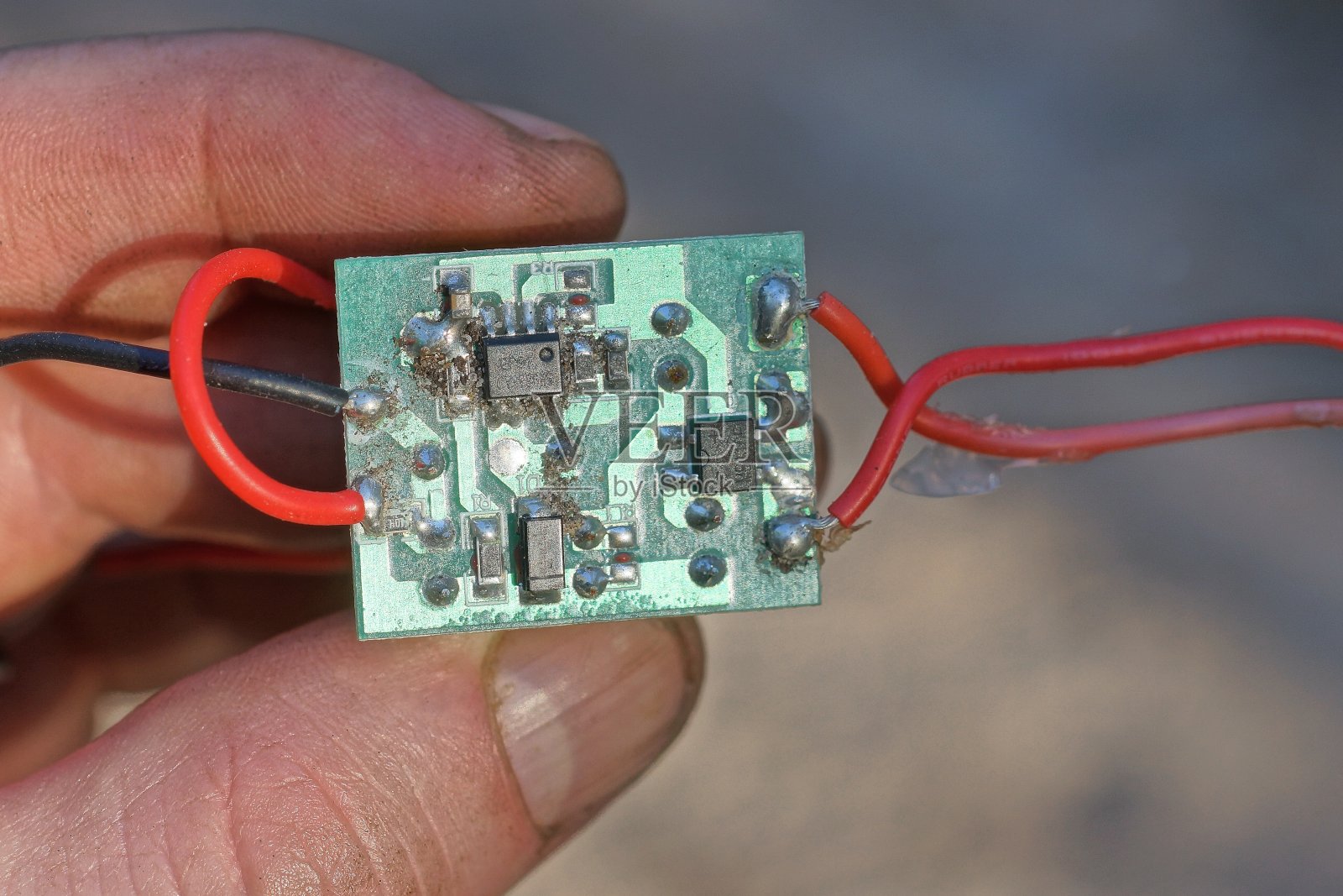 手里拿着一个小的绿色微电路，上面有晶体管和电阻照片摄影图片