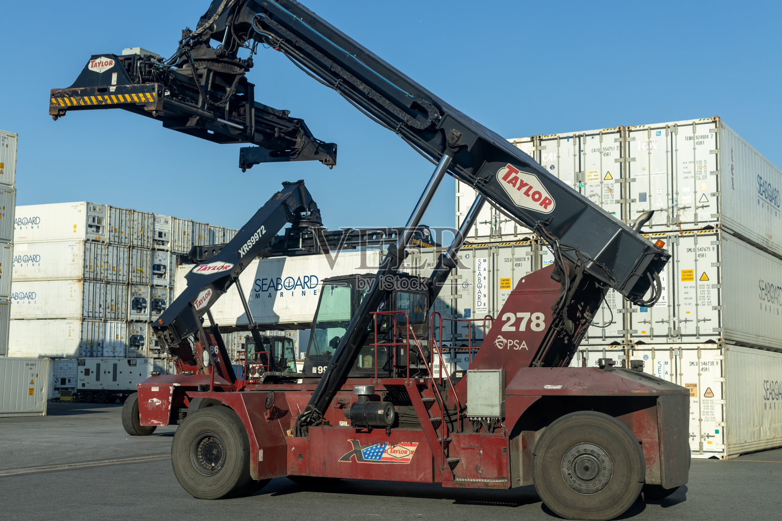 在集装箱堆场工作的叉车，在物流操作中熟练地处理堆放的集装箱。照片摄影图片