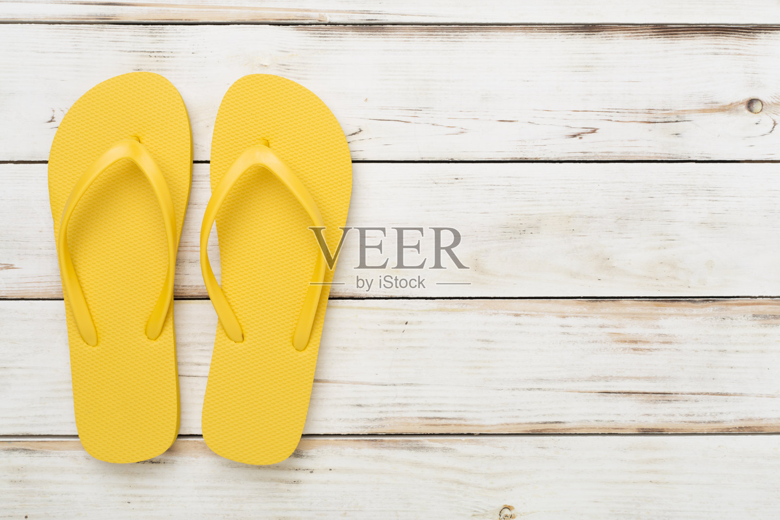 亮黄色人字拖，木质背景，俯视图。夏天的概念照片摄影图片