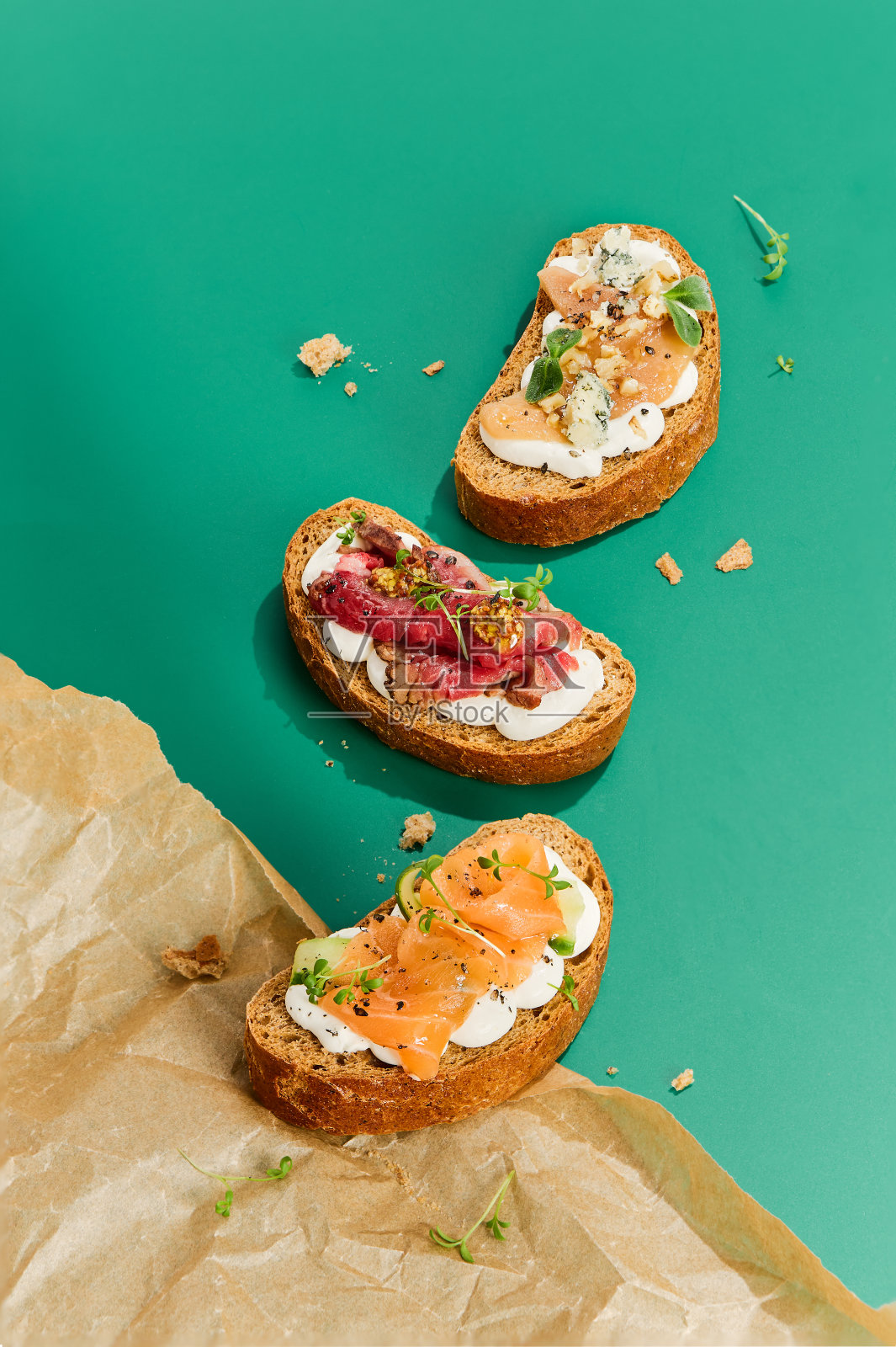 美味什锦烤面包配鲑鱼，烤牛肉，蓝纹奶酪配梨，绿色背景照片摄影图片