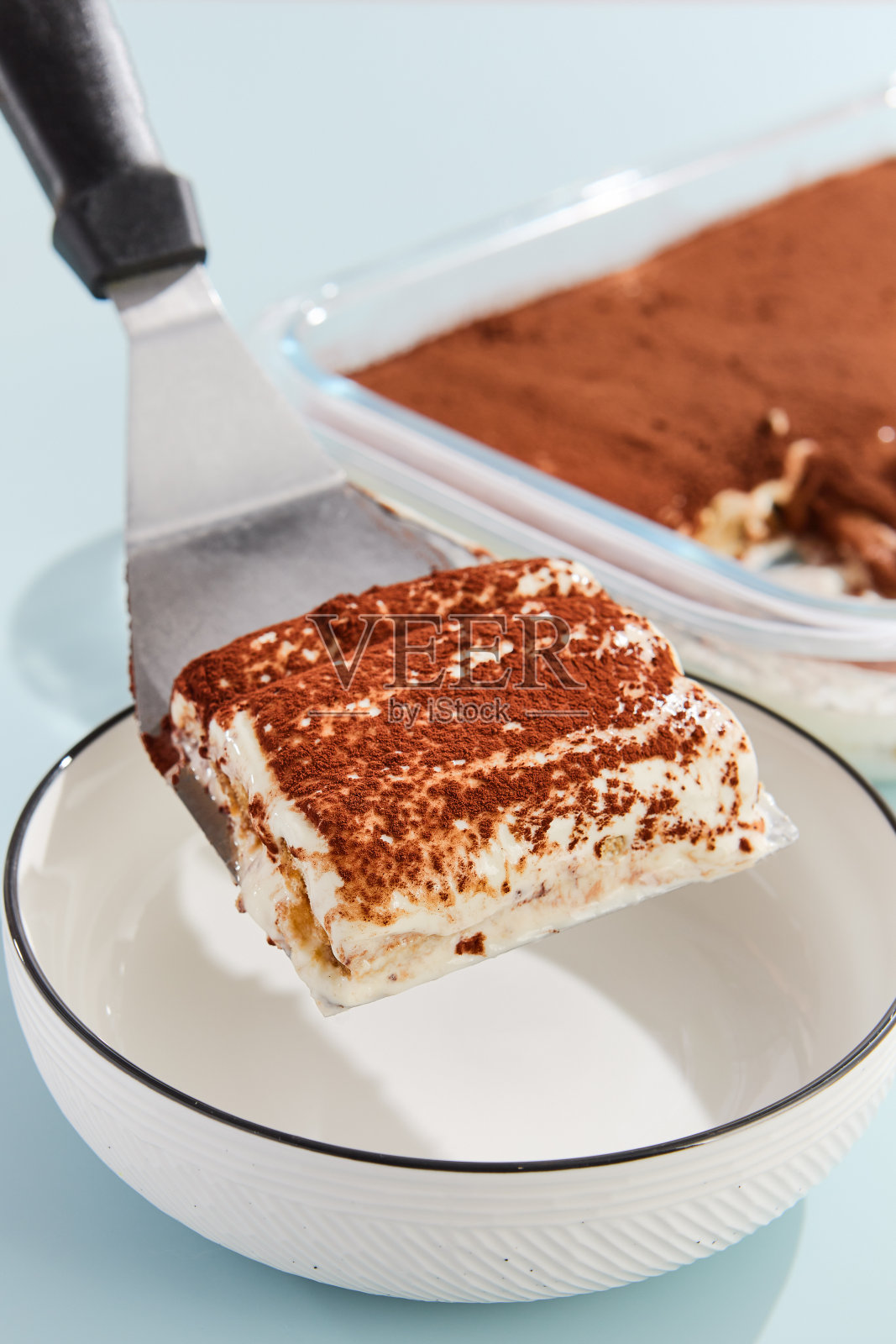 经典的提拉米苏片与可可粉在抹刀之上的白色碗照片摄影图片