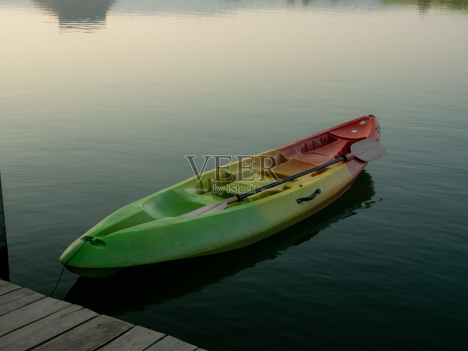 五颜六色的彩虹条纹皮艇在平静的水面上休息。固定在一个由湖上风化的木板制成的木码头上照片摄影图片