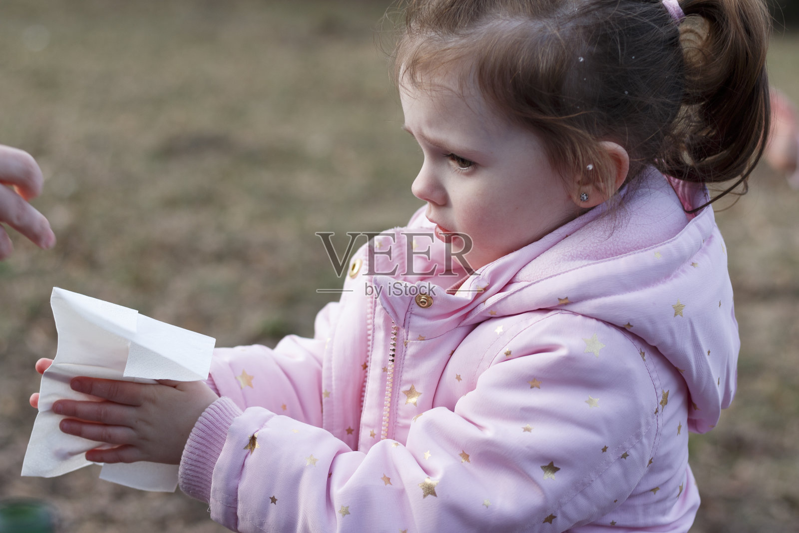在一个没有雪的冬天公园里，悲伤的小女孩用湿餐巾擦手照片摄影图片