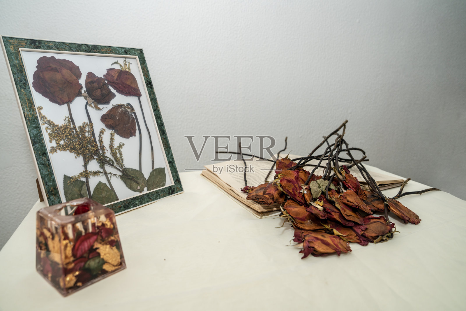 一个美丽的女人用桌子上的死玫瑰制作镜框照片摄影图片