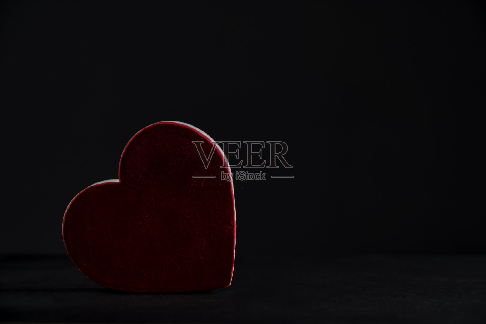 黑色背景上的红心背景光。照片摄影图片