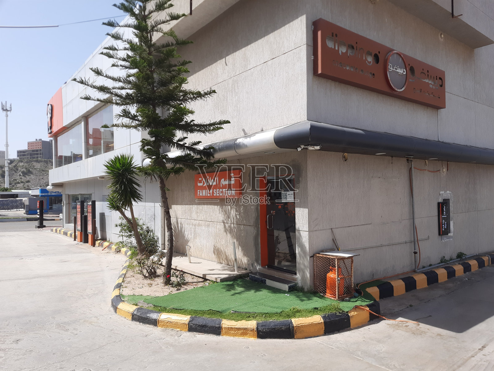 阳光明媚的早晨，Al-Bahah山区旅游城市主干道上的建筑物、商店和汽车，蓝天白云，旅游目的地，商业照片摄影图片