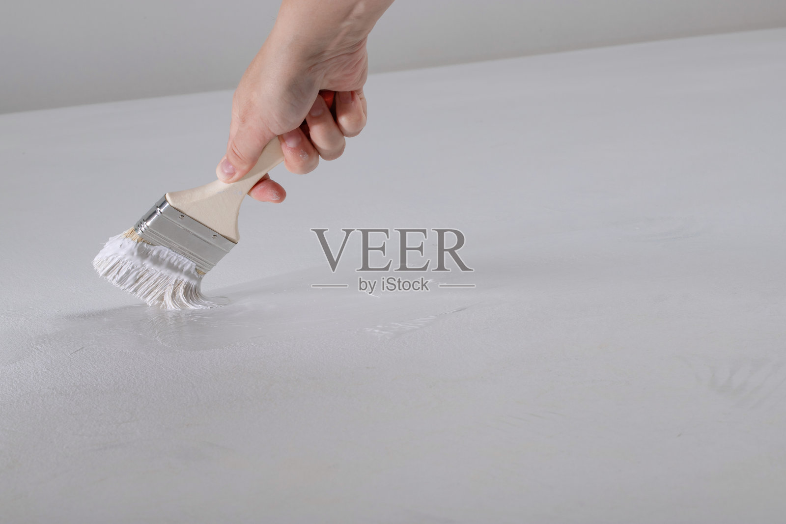 画刷在女人的手里，刷上白色的颜料，画表面照片摄影图片