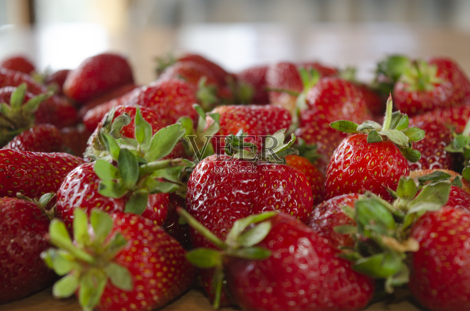 木桌子上的草莓与失焦的家庭背景照片摄影图片