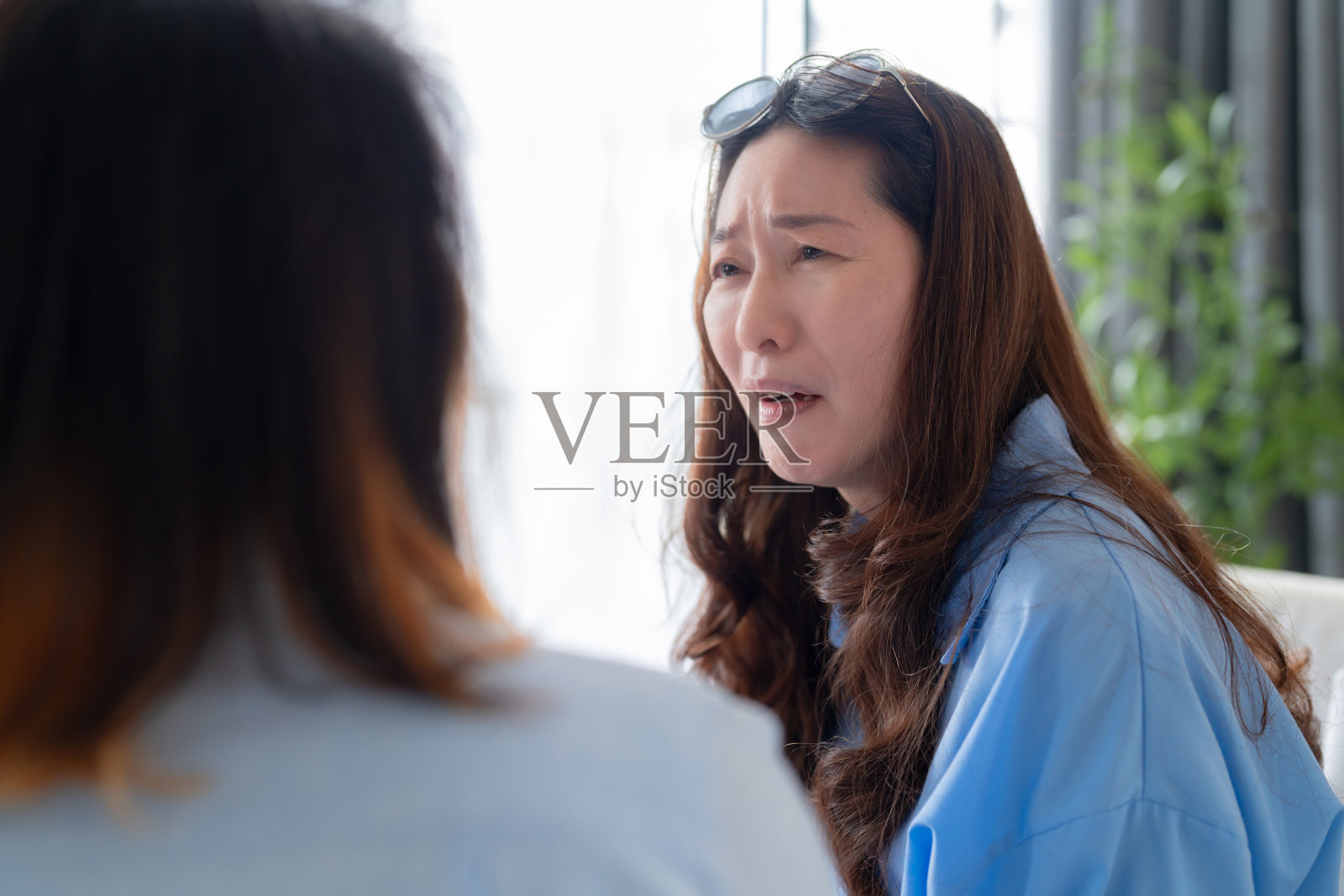 成年女性在分手后安慰她的朋友，悲伤的亚洲女性在客厅的沙发上和朋友聊天，爱和支持朋友的概念照片摄影图片