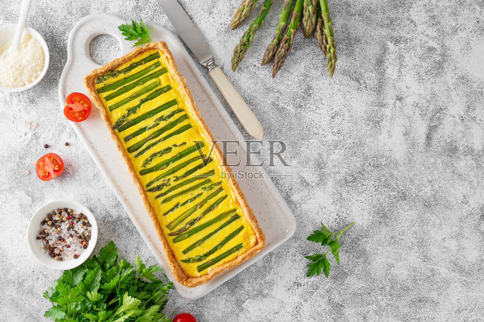 在浅色混凝土背景上的陶瓷板上放上绿芦笋和奶酪，里面有奶油。照片摄影图片