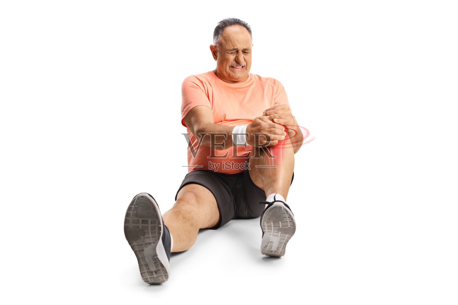 穿运动服的中年男人坐在地上，手扶受伤的膝盖照片摄影图片