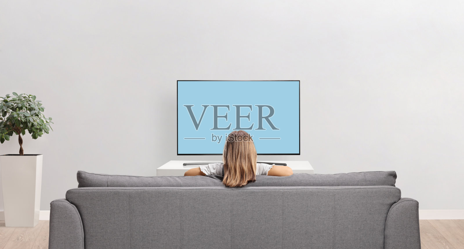 一个女孩坐在沙发上看电视的后视镜照片摄影图片