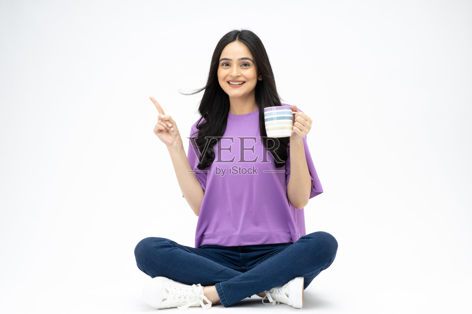 开朗可爱的女人穿着时髦的衣服坐在地板上喝咖啡，空白的空间孤立在白色背景的照片照片摄影图片