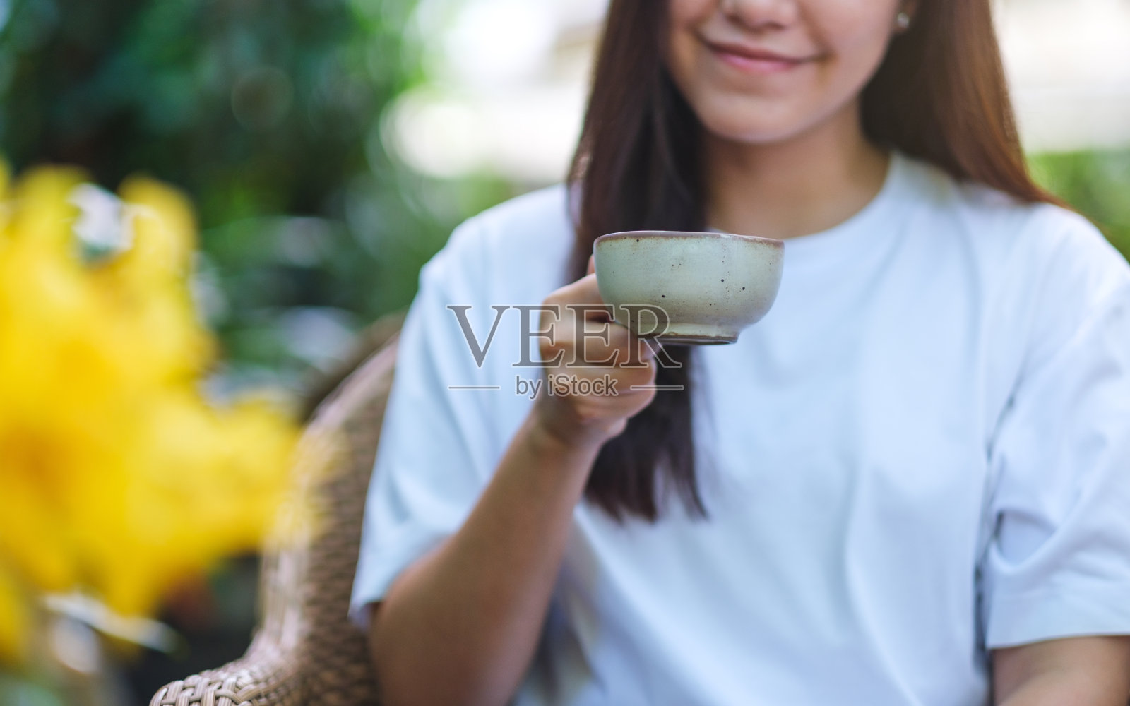 一个年轻女子拿着并喝着咖啡的特写照片照片摄影图片