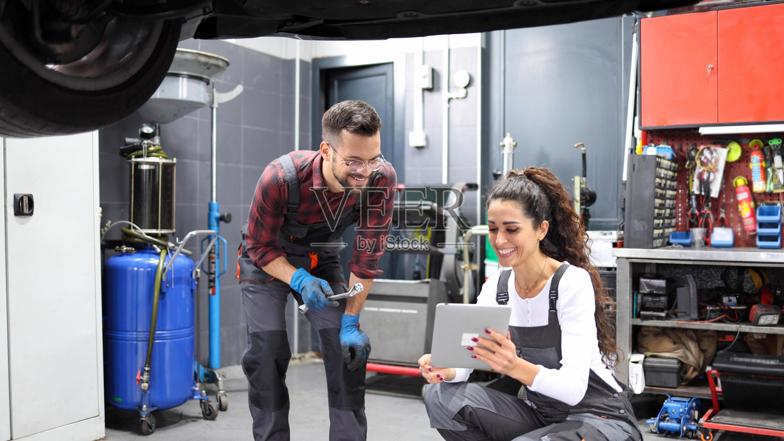 年轻的汽车修理工和他的女同事正在计划如何修理汽车照片摄影图片