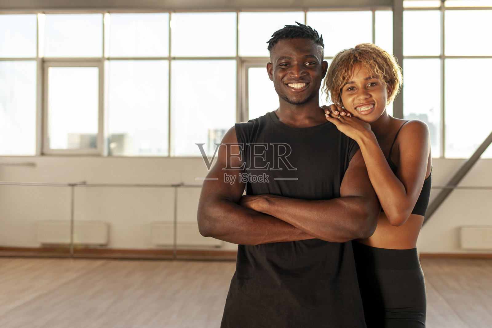 年轻的非裔美国夫妇穿着运动服，双臂交叉地站在体育馆里照片摄影图片