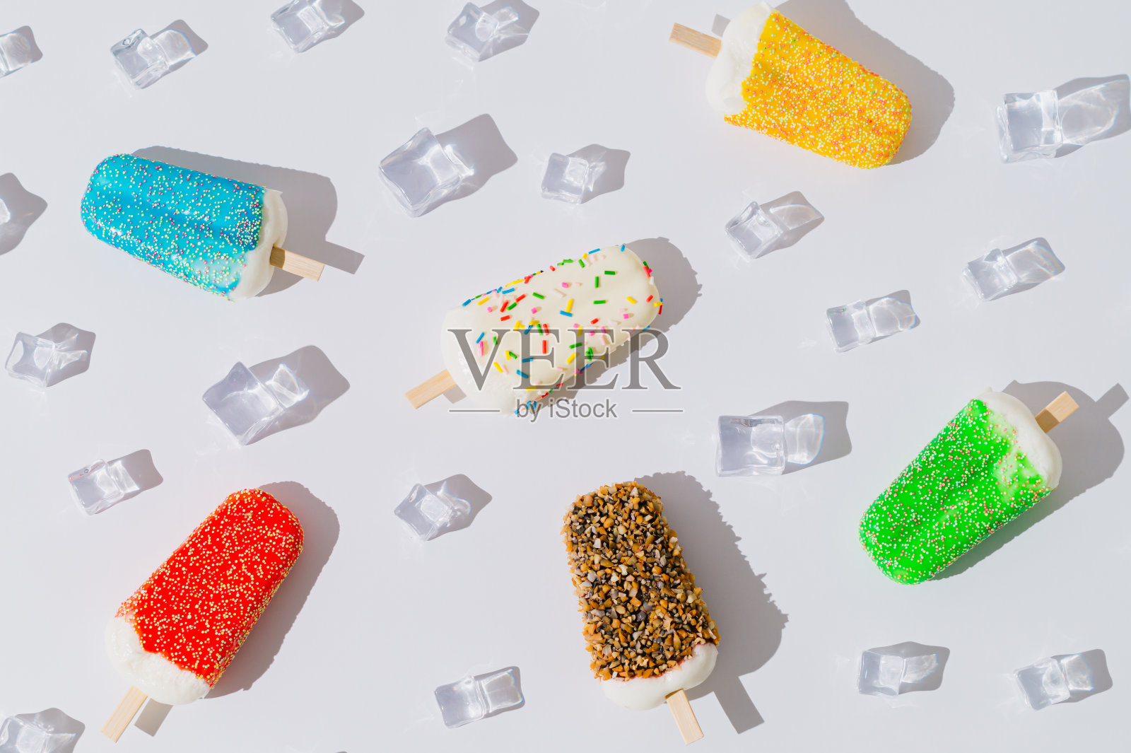 在白色的背景上用五颜六色的雪糕冰棒和冰块做成的夏日图案构图。极具创意的夏季概念。时髦的夏季甜食布局。平的。照片摄影图片