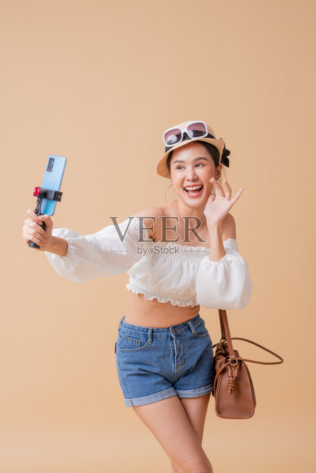 亚洲女青少年视频博客博主旅游网红休闲布手持智能手机与gimball棒生活聊天或交谈，她的追随者通过她的频道，亚洲女性旅游孤立照片摄影图片