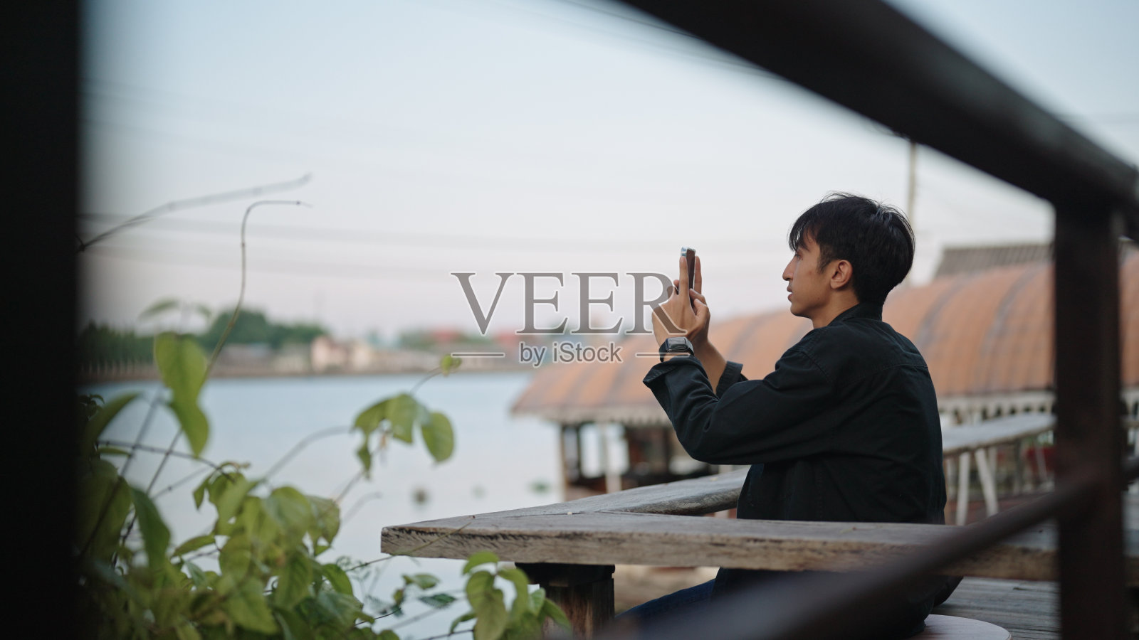 一名男子在河边休息时拍照。照片摄影图片