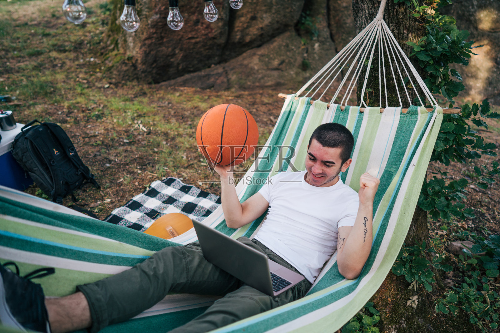 年轻人躺在电脑上看篮球比赛照片摄影图片